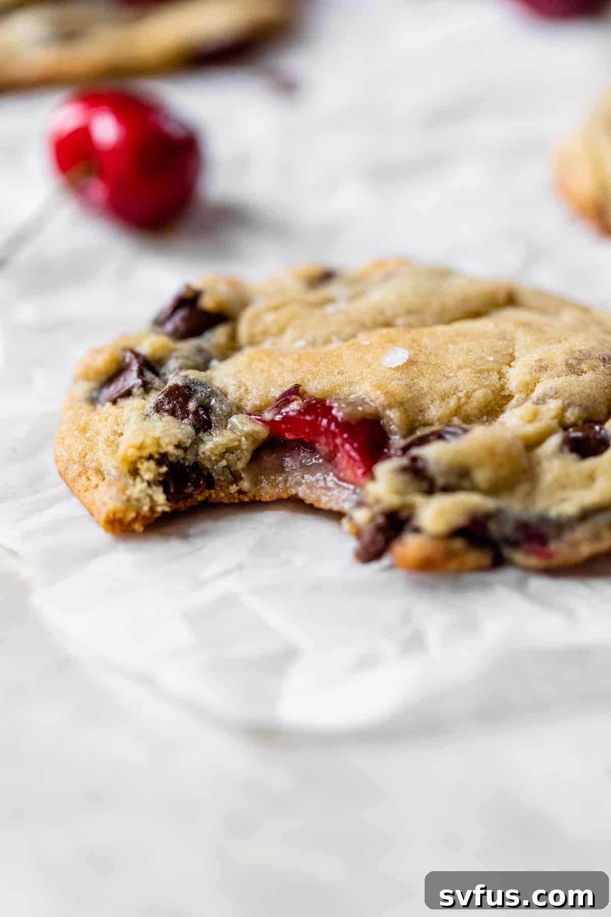 a chocolate chip cookie with cherries in it with a bite taken out of it