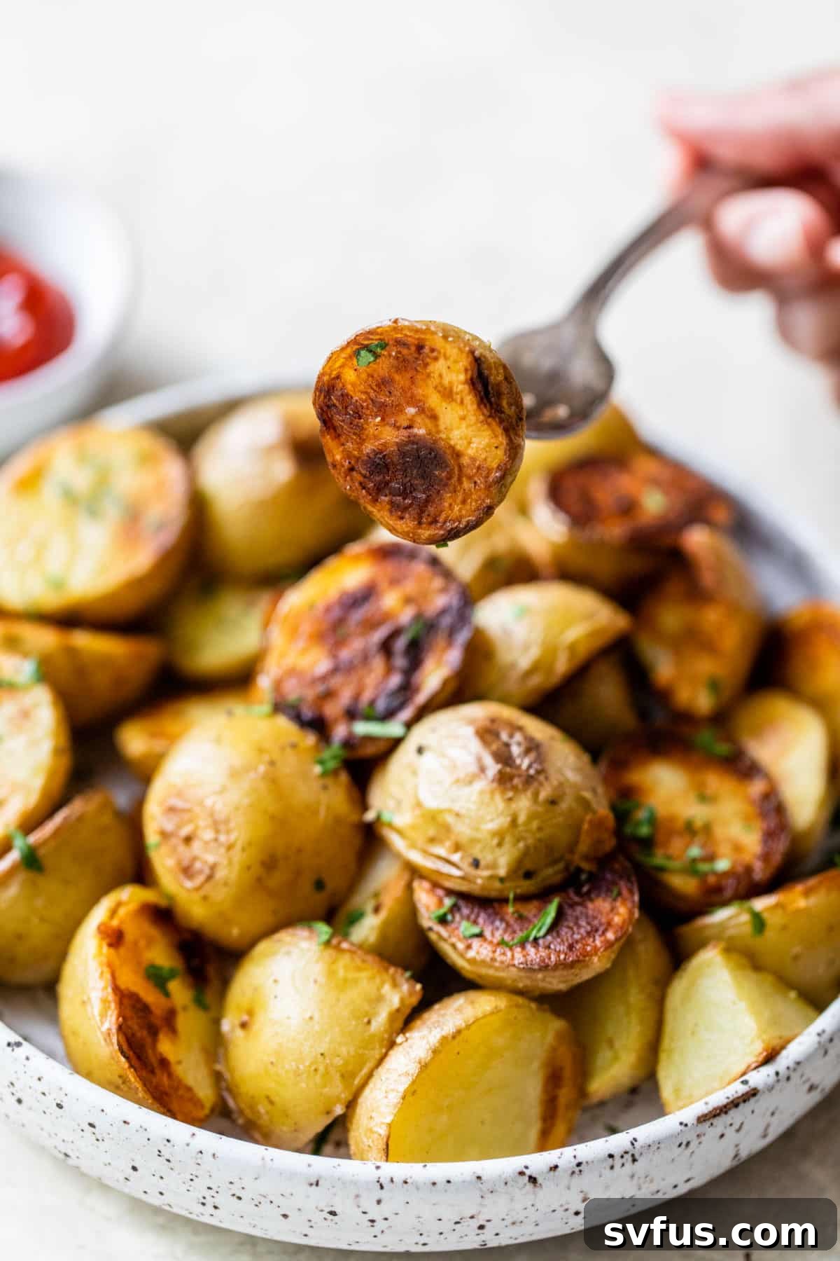 Grilled potatoes on a plate with one potato pierced by a fork, showcasing its tender interior