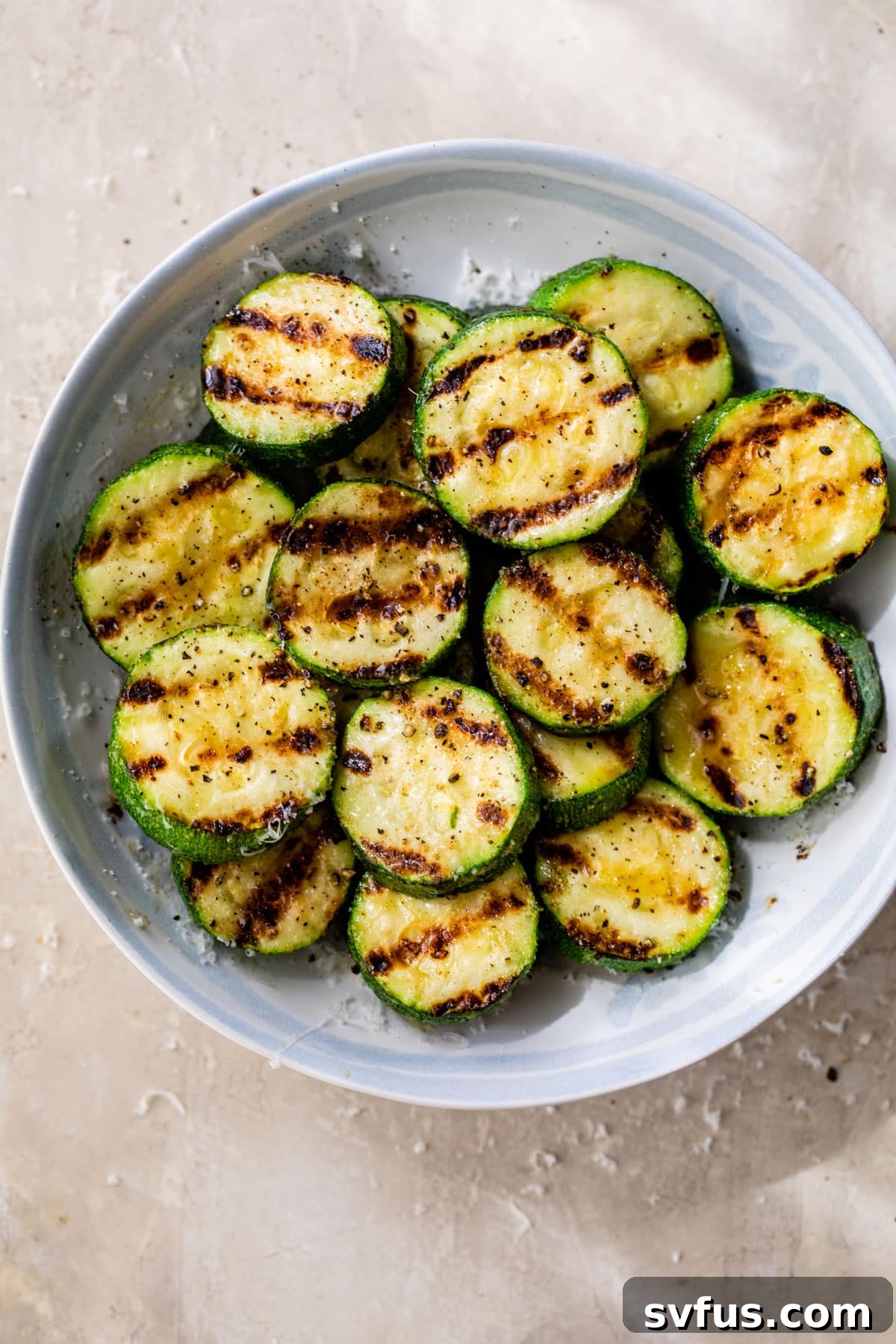 A beautiful overview of grilled zucchini in a serving bowl, garnished with Parmesan cheese