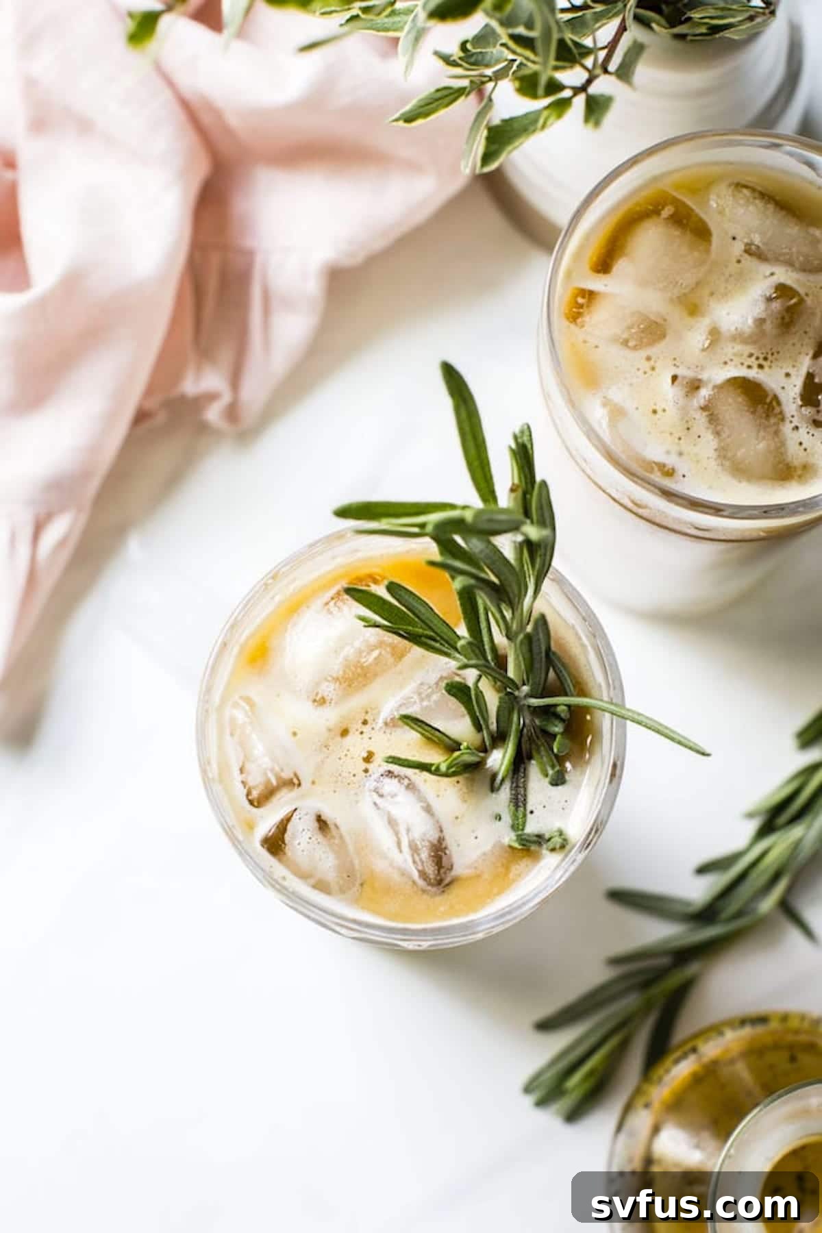 A beautifully presented iced vanilla rosemary latte with a fresh rosemary sprig, ready to be enjoyed.