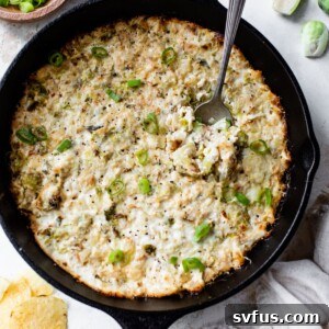 Brussels sprouts dip cooked in a cast iron skillet with a spoon
