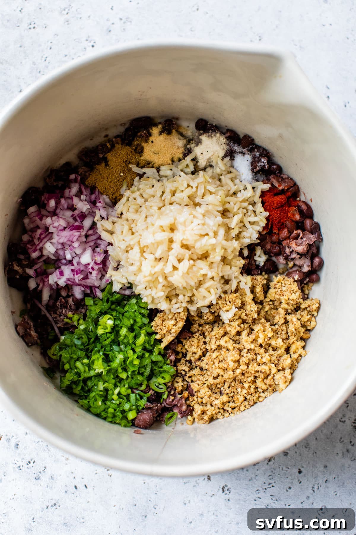 a bowl with all rice, chopped veggies, and spices before the sweet potato is added.