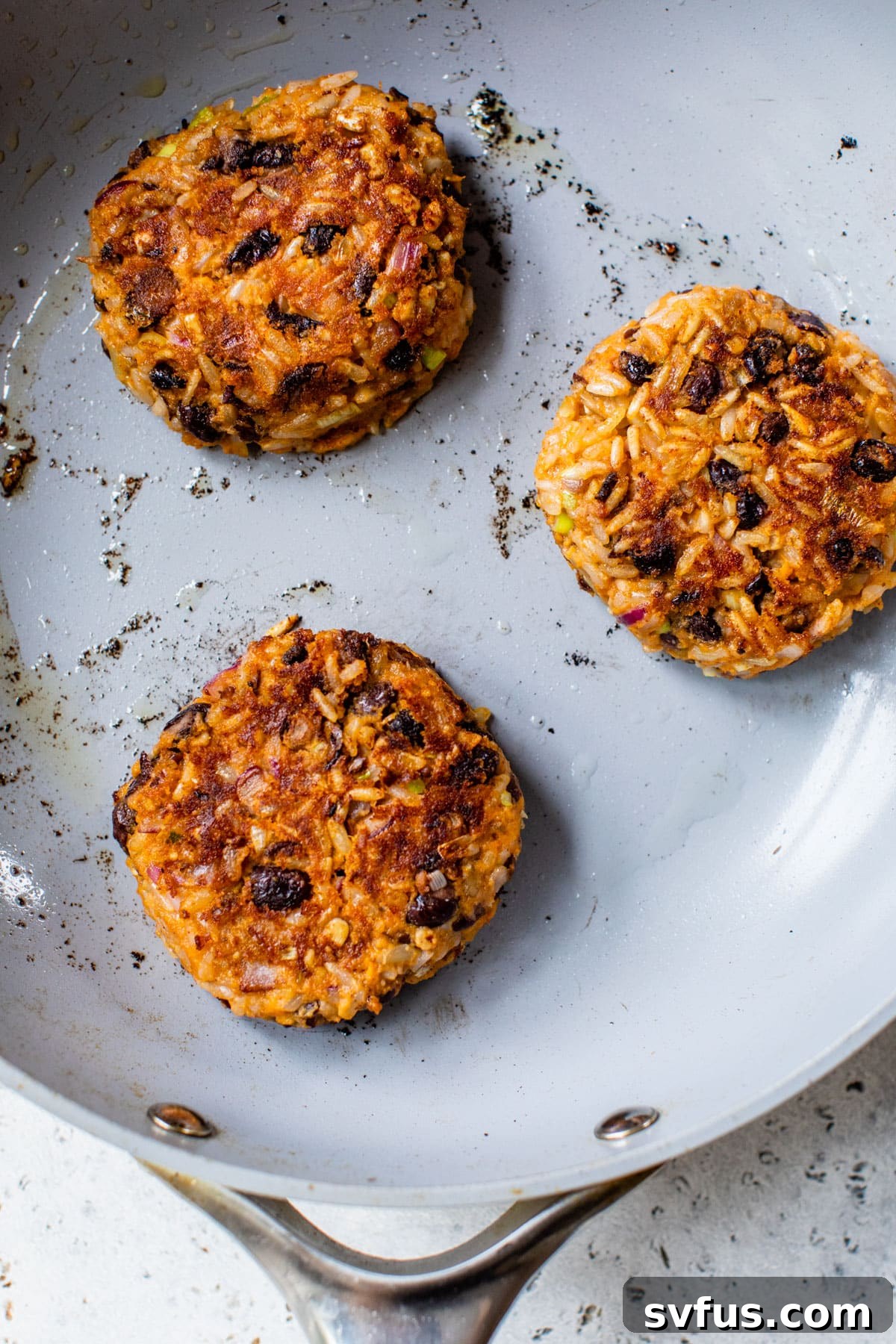 sweet potato black bean burgers frying in a skillet, sizzling and browning.