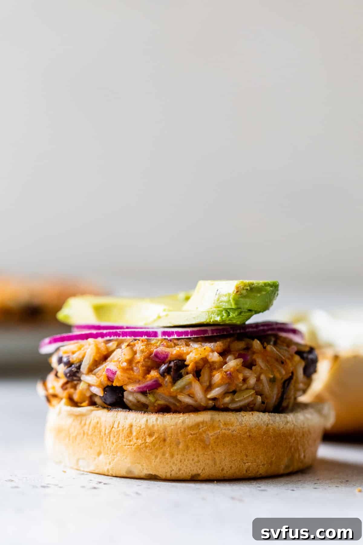 sweet potato black bean burger with an avocado slice, showcasing a gourmet presentation.