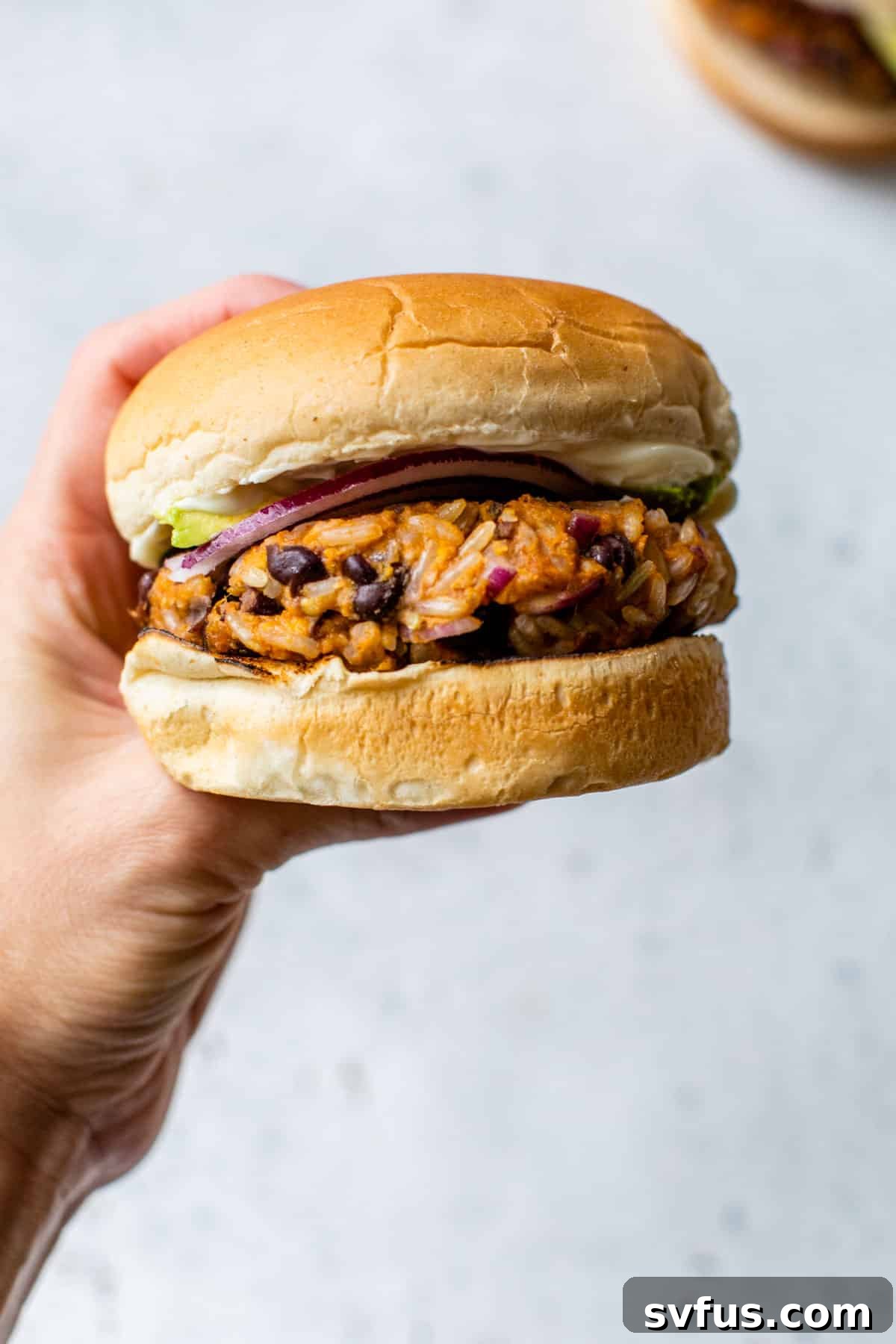 sweet potato black bean burger held up with a hand, showcasing its perfect texture.