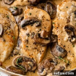 close up photo of cooked chicken breast in a skillet with a creamy mushroom sauce