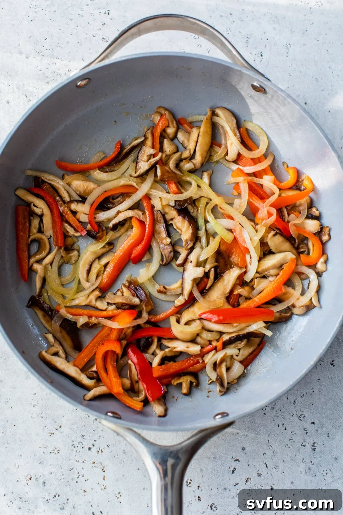onion, peppers, and mushrooms cooking in a large skillet