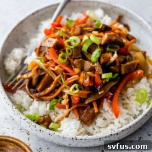 a plate of seitan stir fry with a fork