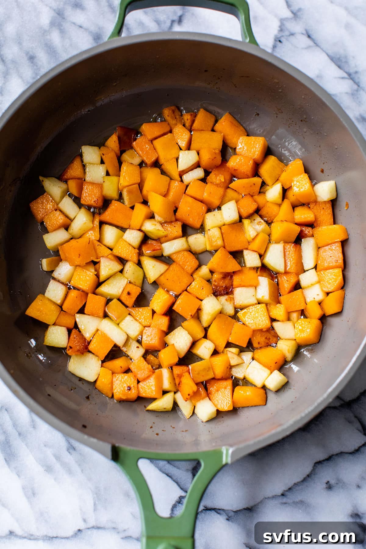 butternut squash pieces cooking in a skillet