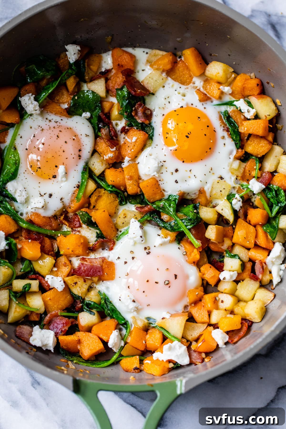 a close-up of butternut squash hash with 3 eggs in a skillet