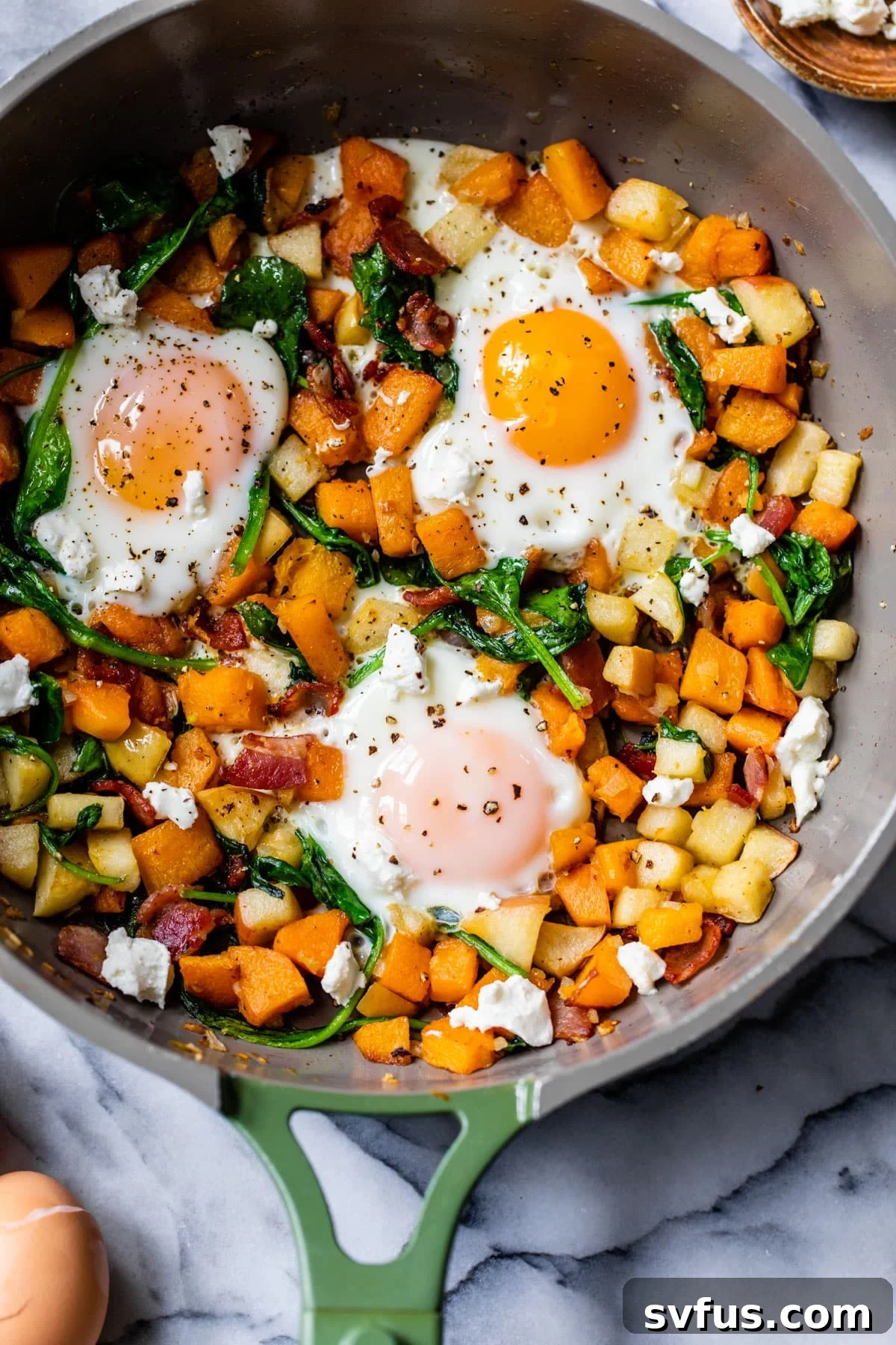 butternut squash hash with 3 eggs in a skillet