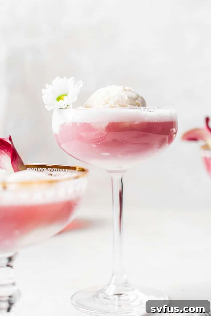 A hand reaching for a glass of Hibiscus Ice Cream Float, ready to enjoy.