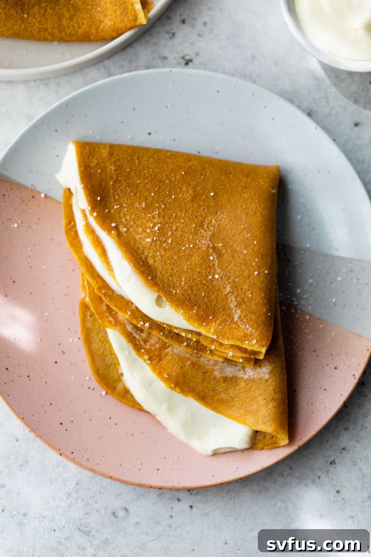 A simple yet elegant stack of two pumpkin crepes resting on a white plate, invitingly presented.