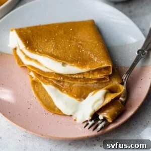 Two crepes stacked on top of each other on a plate with a fork