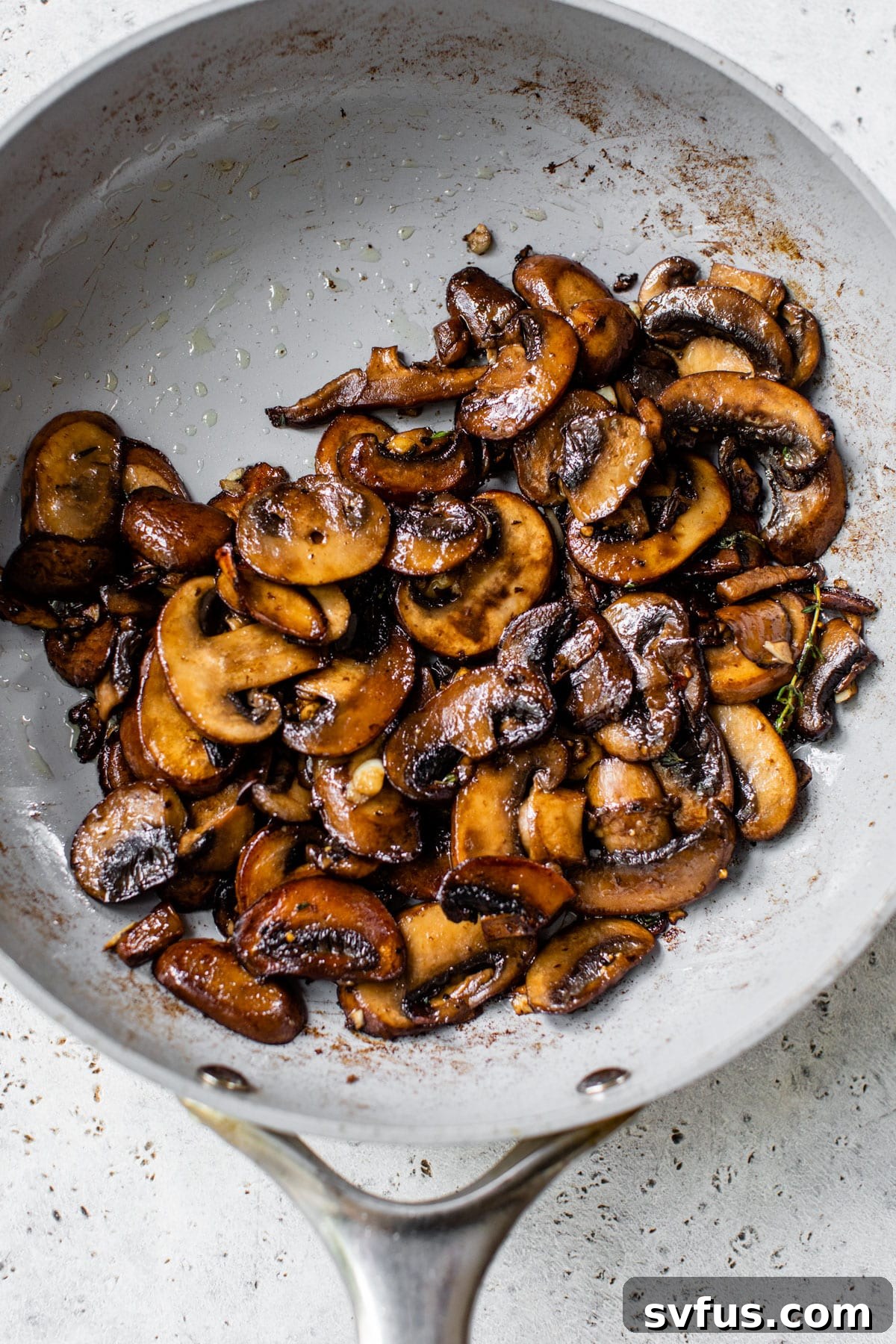 Cooked, caramelized mushrooms with garlic, thyme, and balsamic in a skillet, ready for topping.