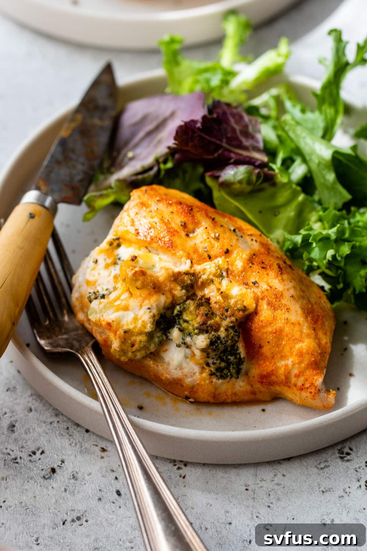 A beautifully cooked stuffed chicken breast, sliced to reveal the creamy filling, presented on a plate.