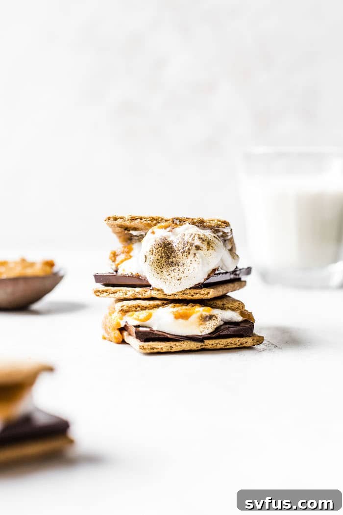 A hand holds a delicious, gooey Indoor Pumpkin S'mores, highlighting the pumpkin layer.