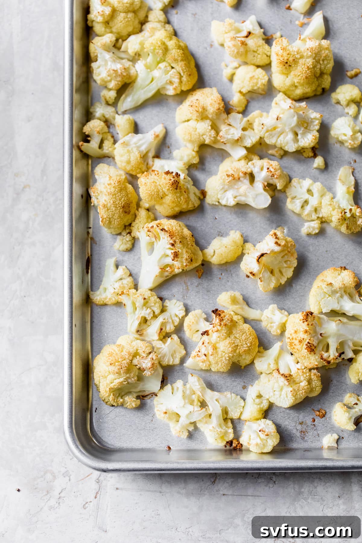 Roasted cauliflower florets spread out on a baking sheet, golden brown and tender, ready for the soup.