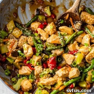 A skillet filled with cooked chicken and vegetables coated in a sauce and topped with sesame seeds