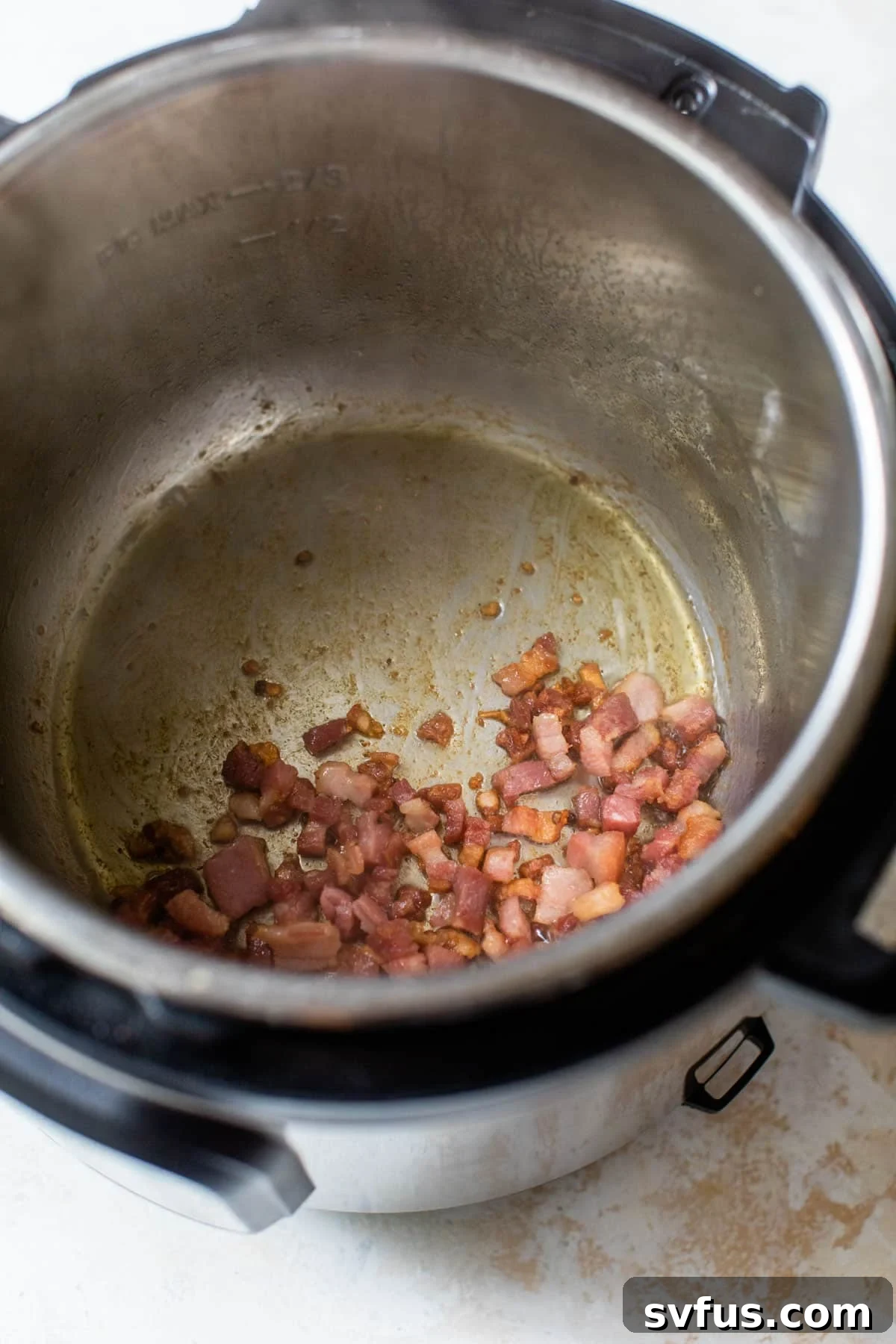 Diced pancetta pieces sizzling and turning golden in the Instant Pot during the sautéing process.
