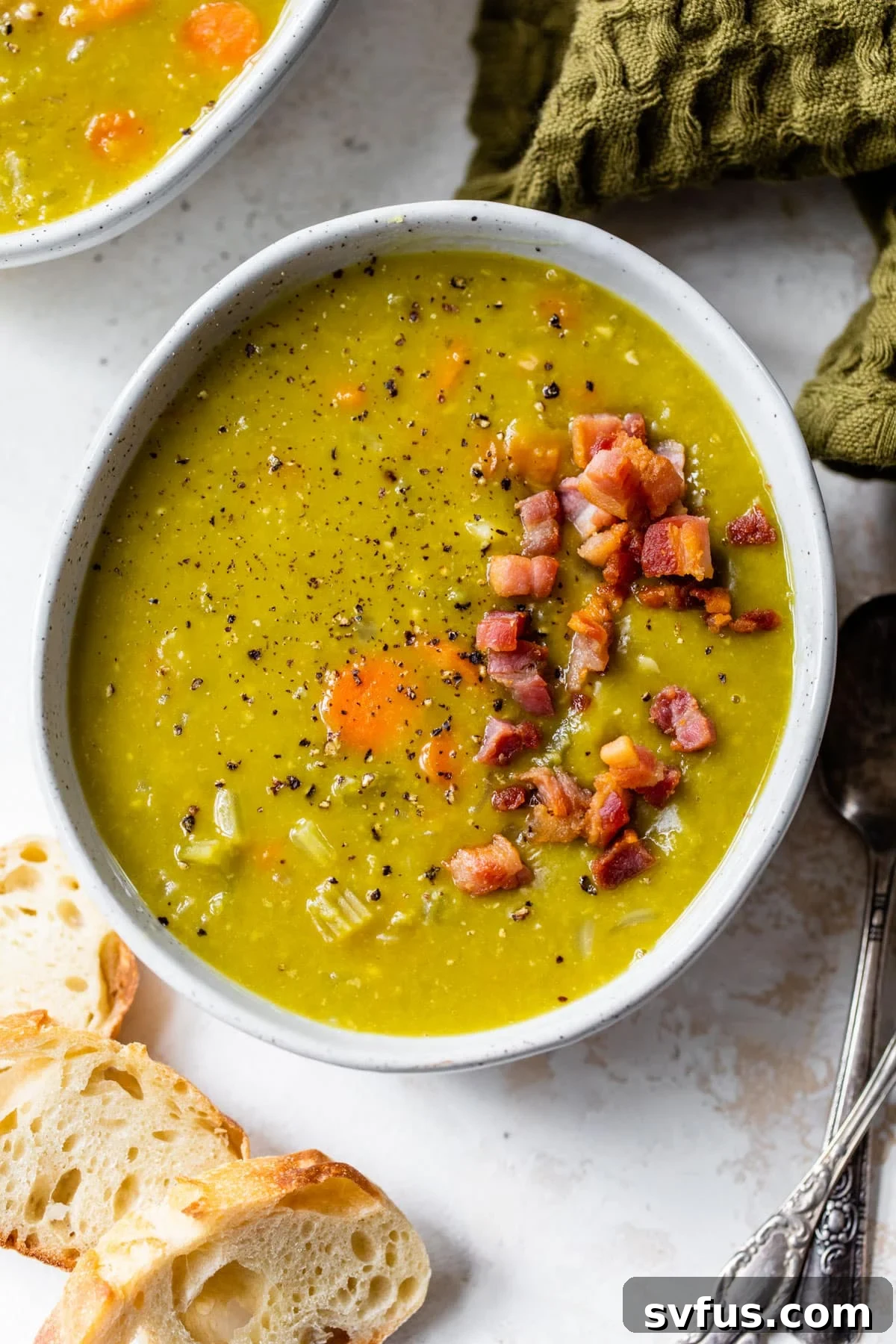 A serving of Instant Pot Split Pea Soup in a bowl, topped generously with more crispy pancetta, ready to be enjoyed.