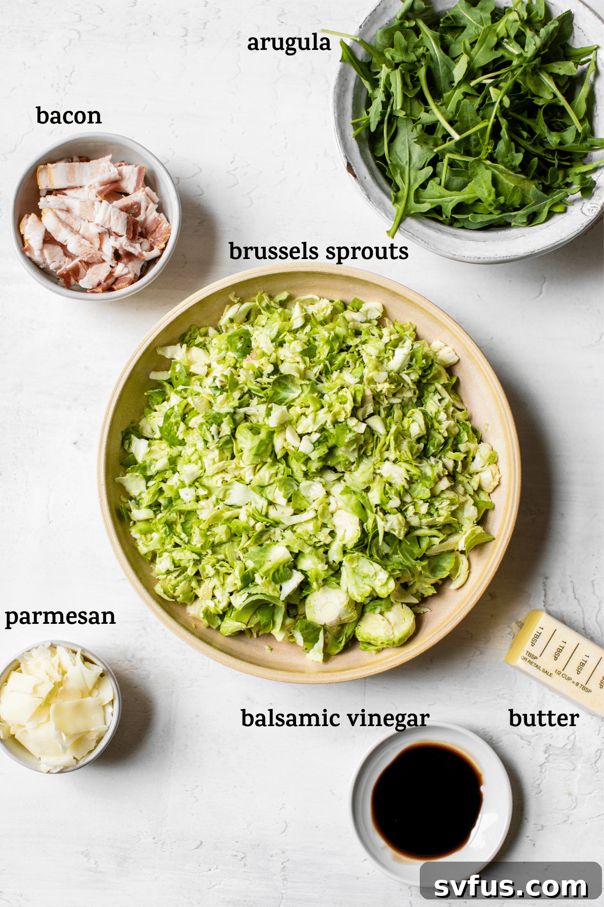 A large bowl of fresh Brussels sprouts and arugula salad, garnished with crispy bacon and cheese