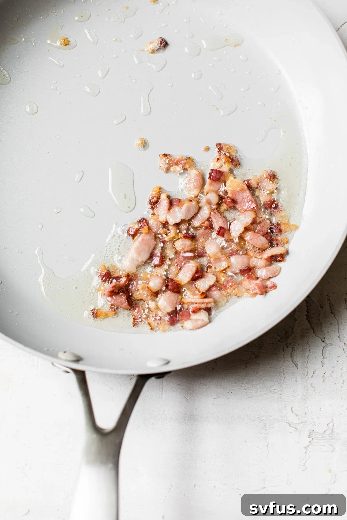 Chopped bacon sizzling and browning in a large nonstick skillet