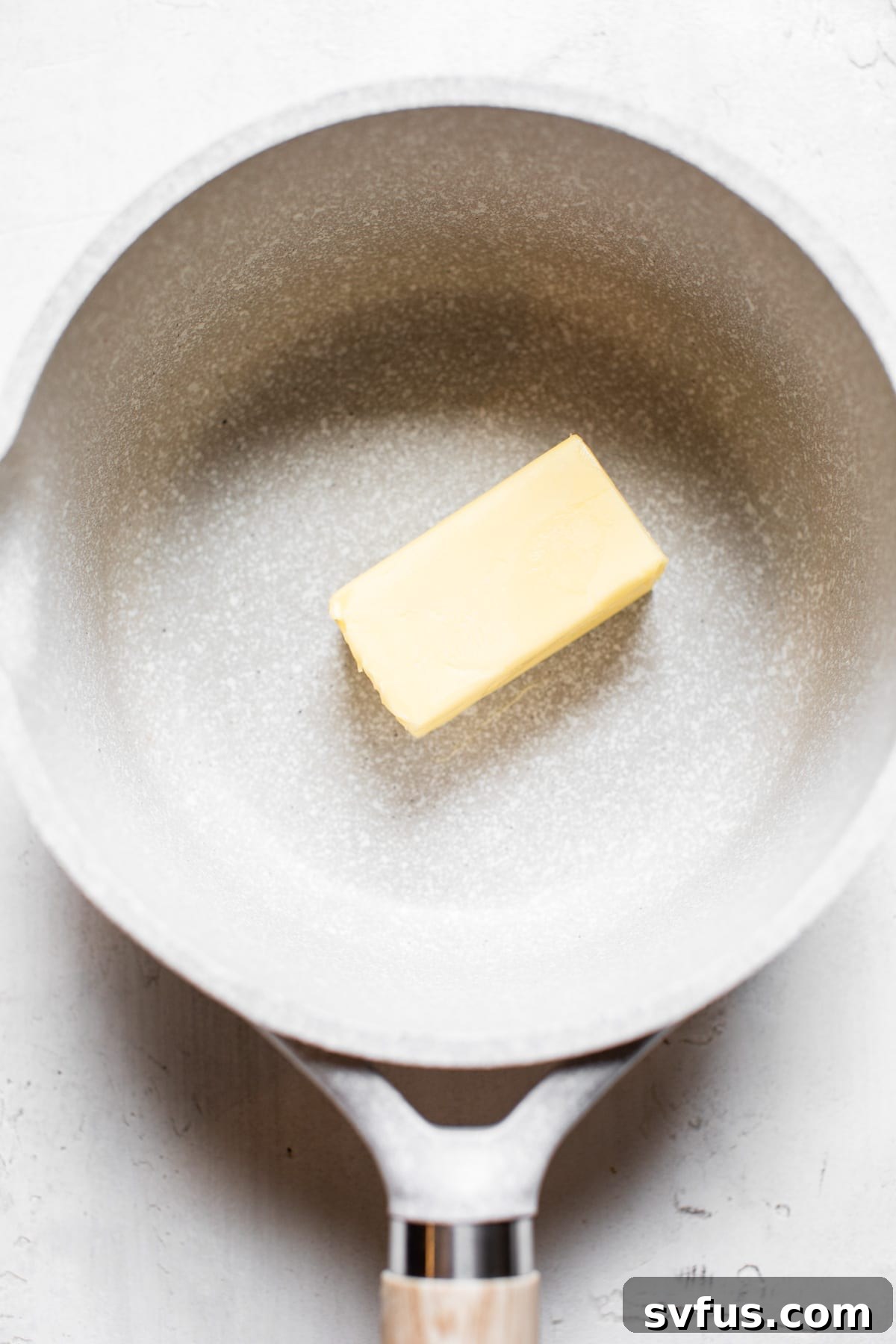 Cubes of butter melting in a stainless steel saucepan over medium heat