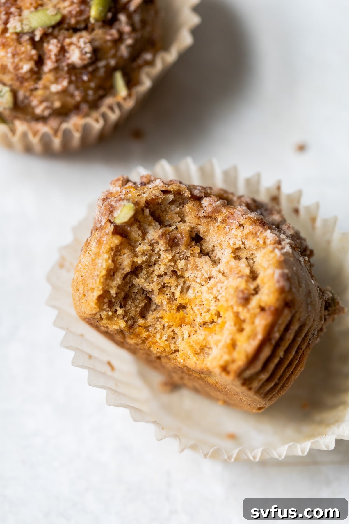A delicious healthy sweet potato muffin with a bite taken out of it, revealing its moist interior and the delightful crumb topping.
