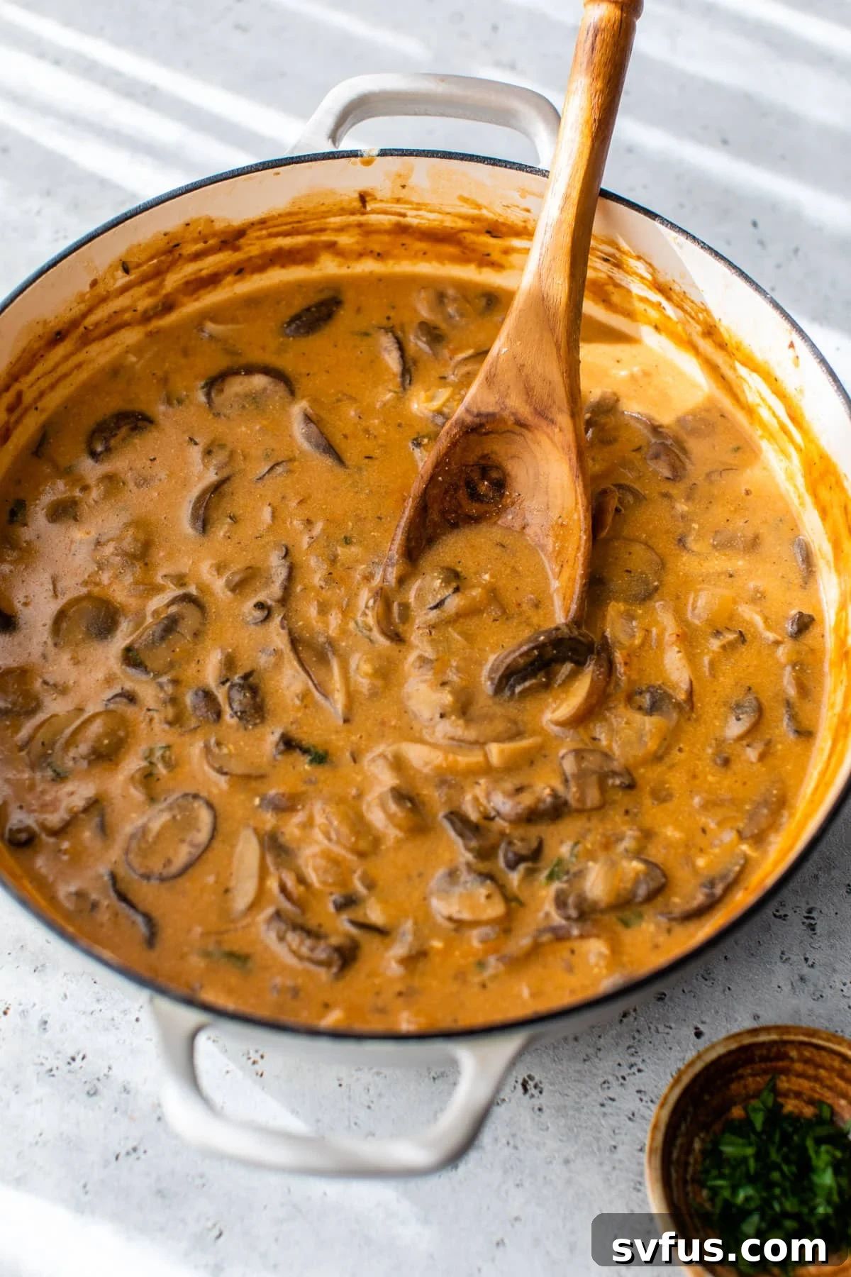 mushroom stroganoff inside a dutch oven with a wooden spoon