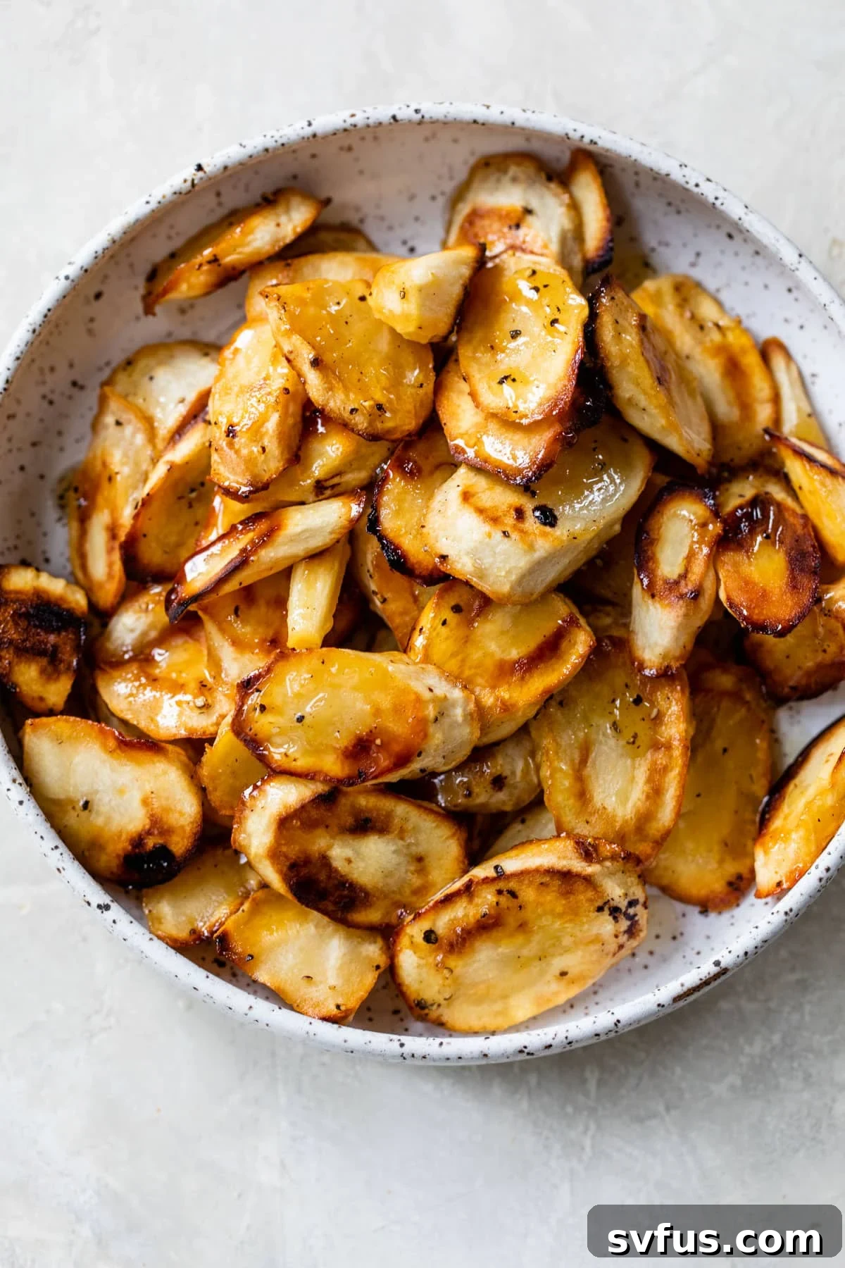 A bowl of freshly roasted honey parsnips, glistening with glaze and ready for serving.