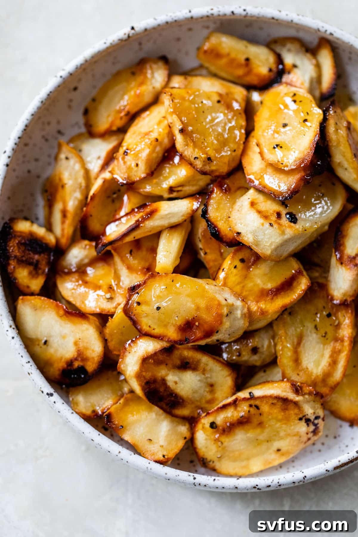 A bowl of honey roasted parsnips ready to be stored or served, highlighting their golden-brown color.
