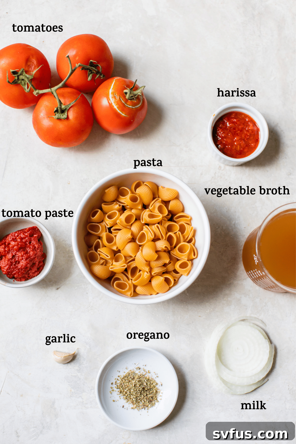 A selection of fresh ingredients including tomatoes, onion, garlic, and spices laid out on a rustic table surface, ready for cooking.