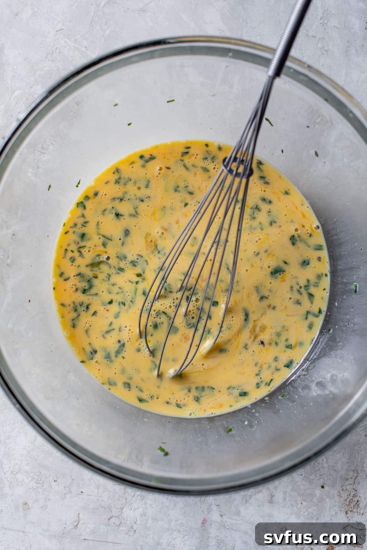 eggs, milk, and spices whisked together in a glass bowl