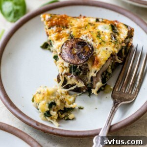 a slice of spinach mushroom quiche on a plate with a fork