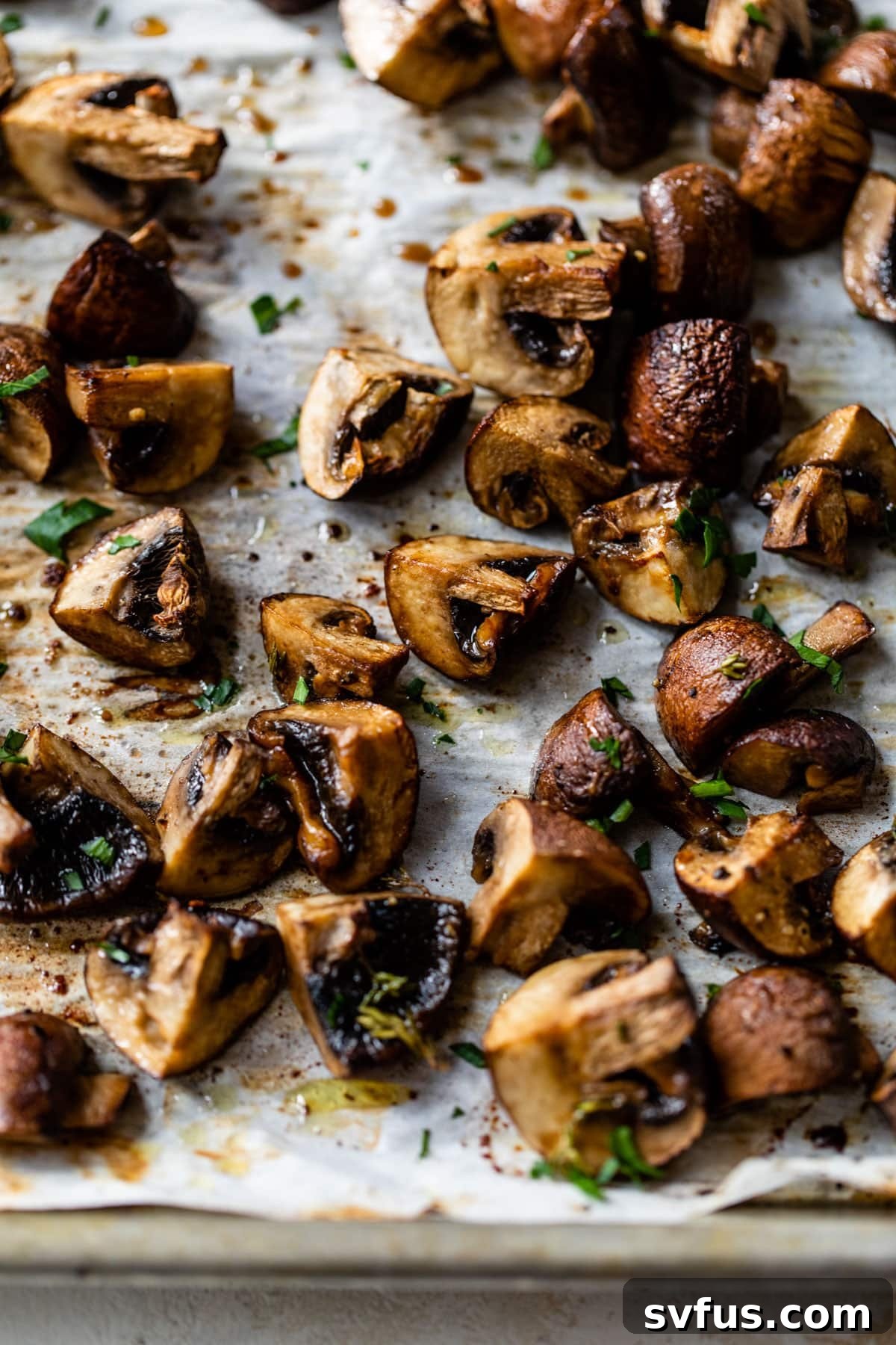 close-up of chopped mushrooms on a parchment lined baking sheet with parsley and balsamic vinegar