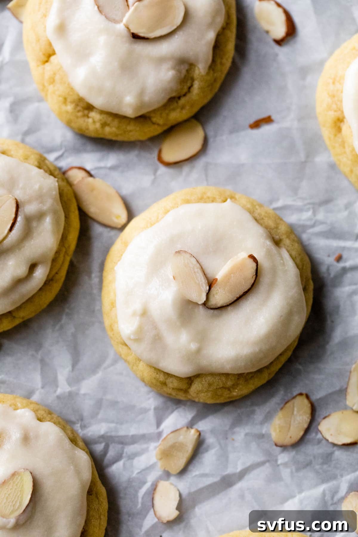 Close-up of a beautifully iced almond sugar cookie, topped with slivered almonds.