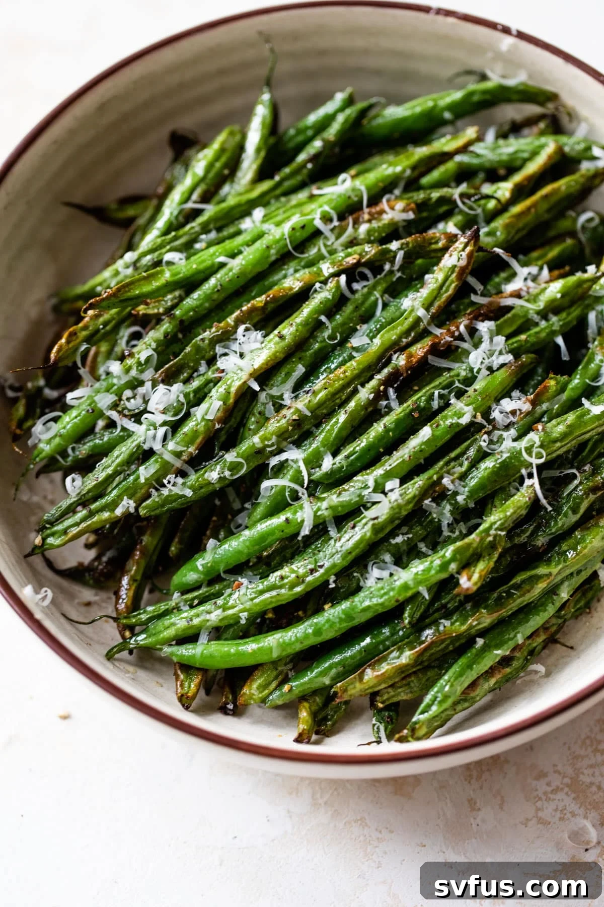 air fryer green beans in a bowl with grated cheese on top