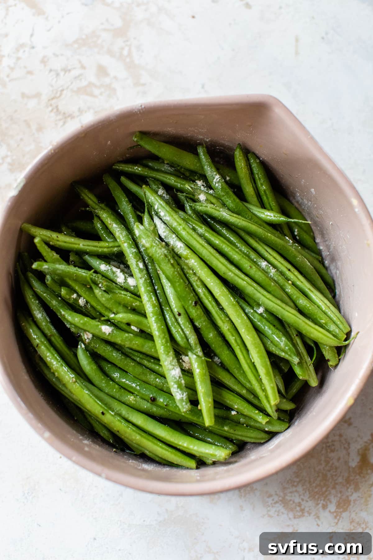 green beans in a bowl with salt and other spices on top