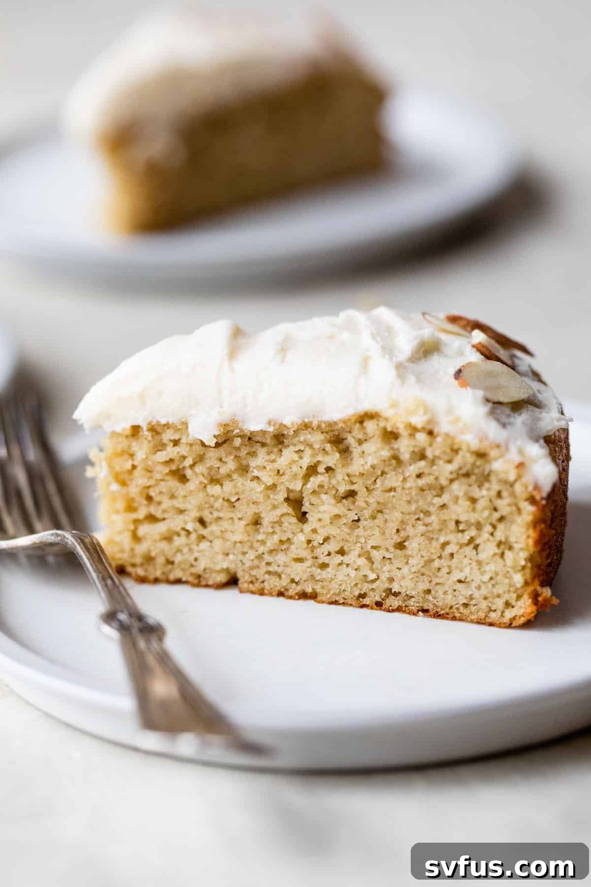 a side view slice of almond flour vanilla cake on a plate with a fork