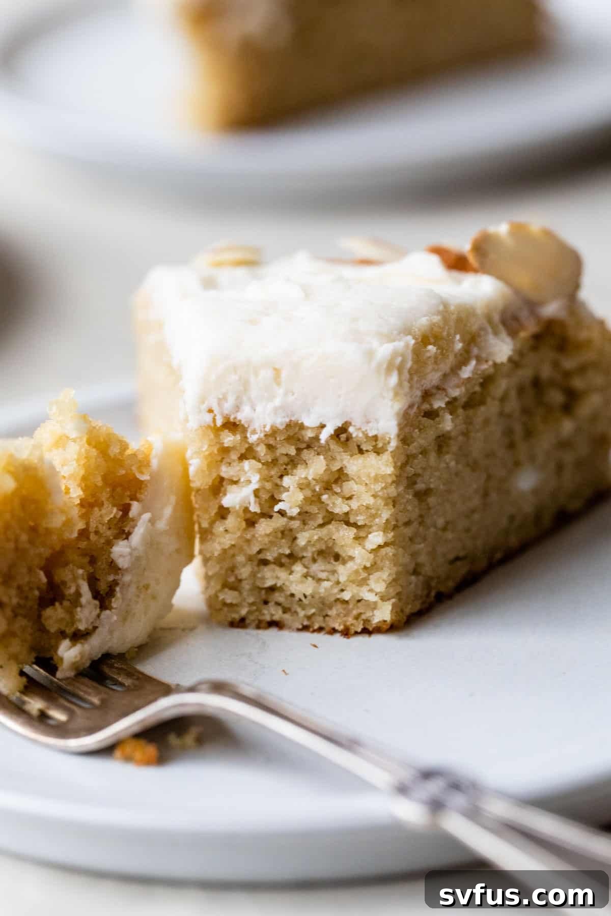 close-up of a slice of almond flour vanilla cake with a bite taken out on a plate with a fork