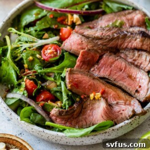 side view of Thai steak salad in a bowl topped with sliced sirloin steak