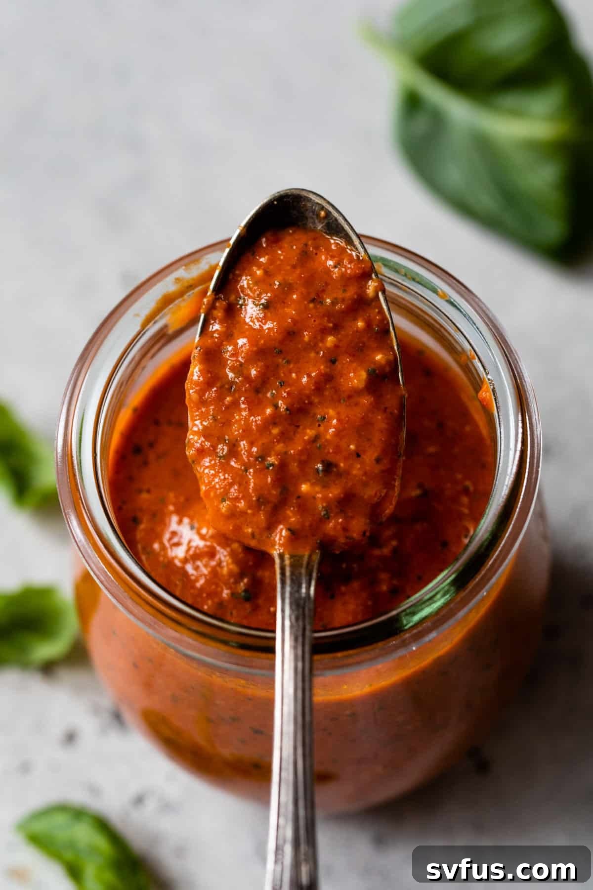 a spoonful of vibrant red pepper pesto in a jar