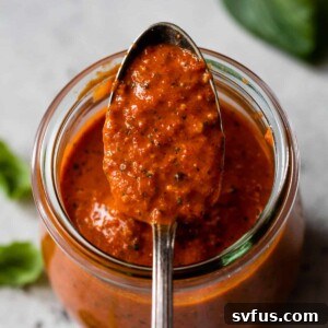 a spoonful of vibrant red pepper pesto in a jar