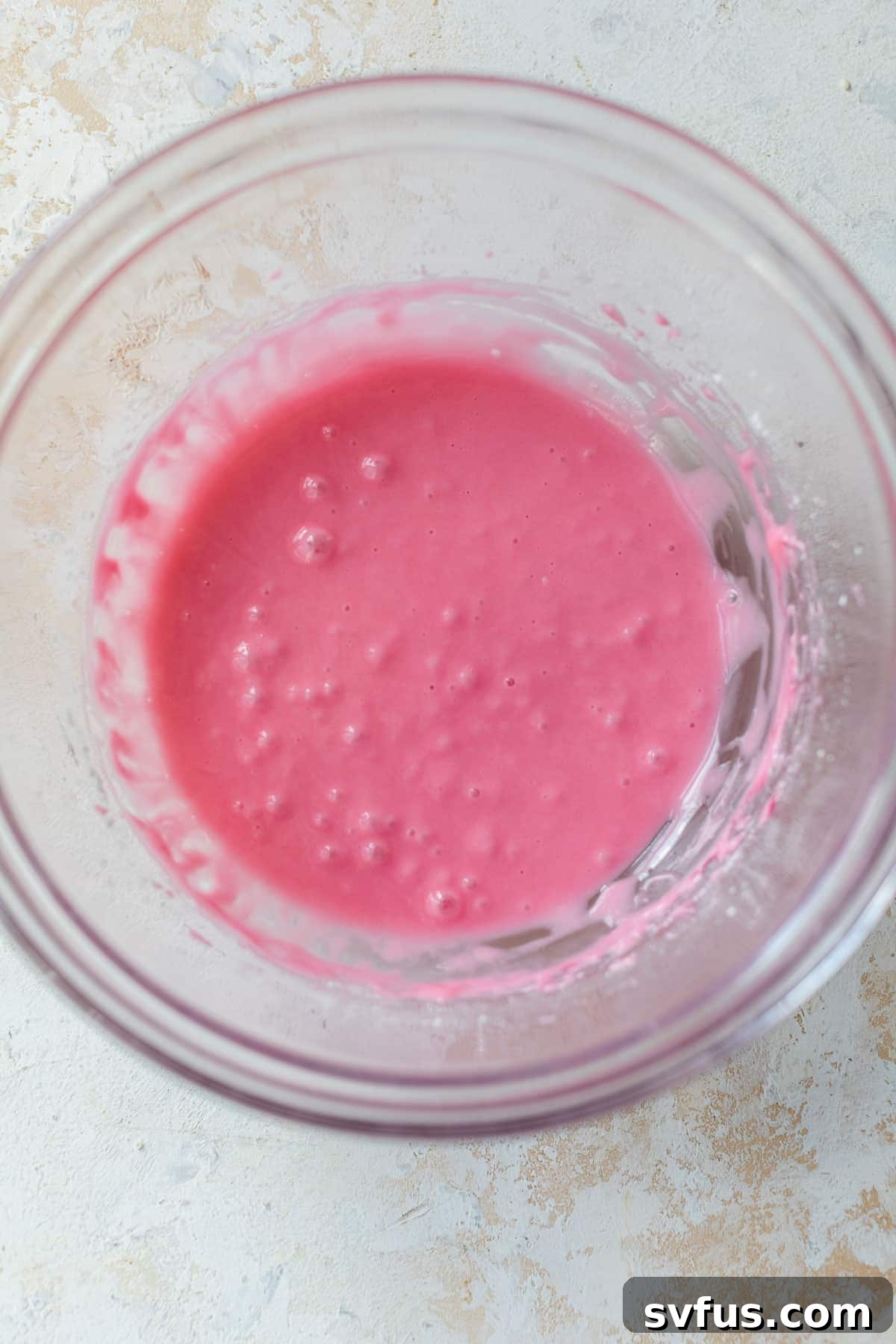 Overhead view of a bowl containing smooth, perfectly pink cranberry glaze, ready to be drizzled.
