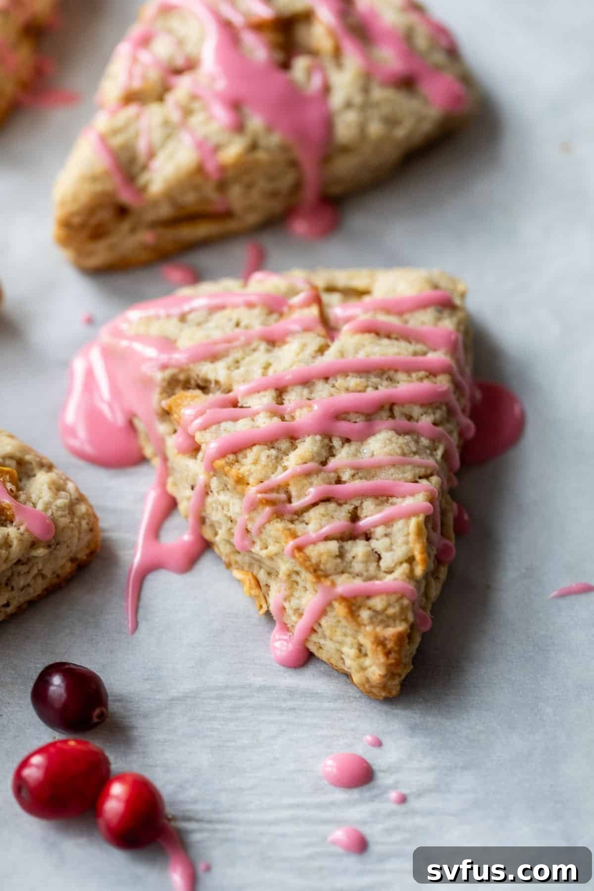 Side view of a single vegan Apple Cranberry Scone drizzled with pink cranberry glaze.