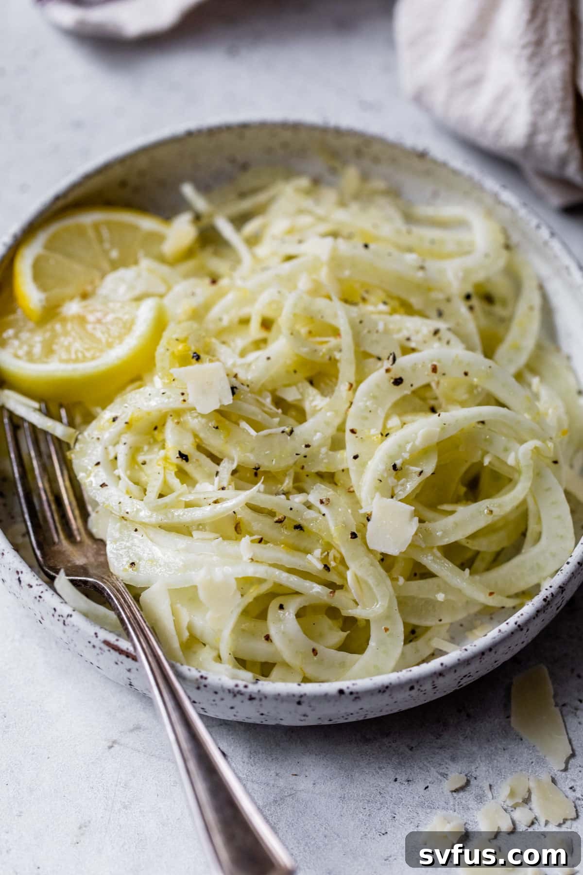 A close-up of the fennel salad on a plate with lemon slices and a fork, emphasizing its fresh ingredients.