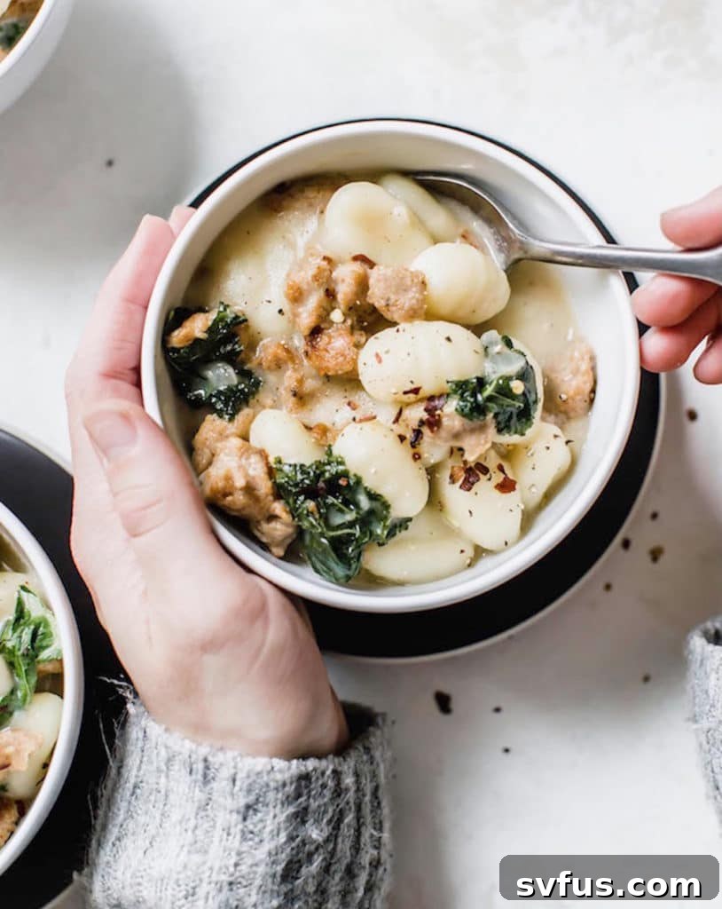 A bowl of creamy one-pot gnocchi with sausage and kale, garnished with fresh herbs.