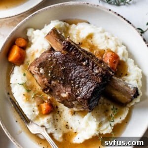 Overview of short ribs on top of mashed potatoes and gravy on a plate with a fork