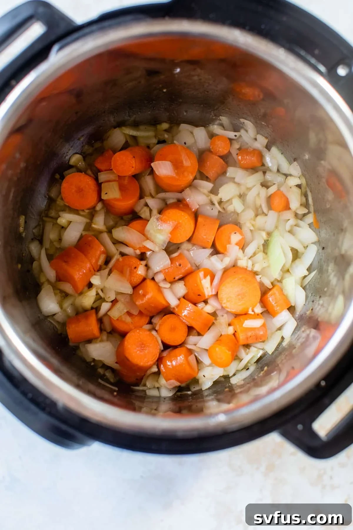Chopped carrots and onions sautéing in the Instant Pot, forming the base of the gravy.